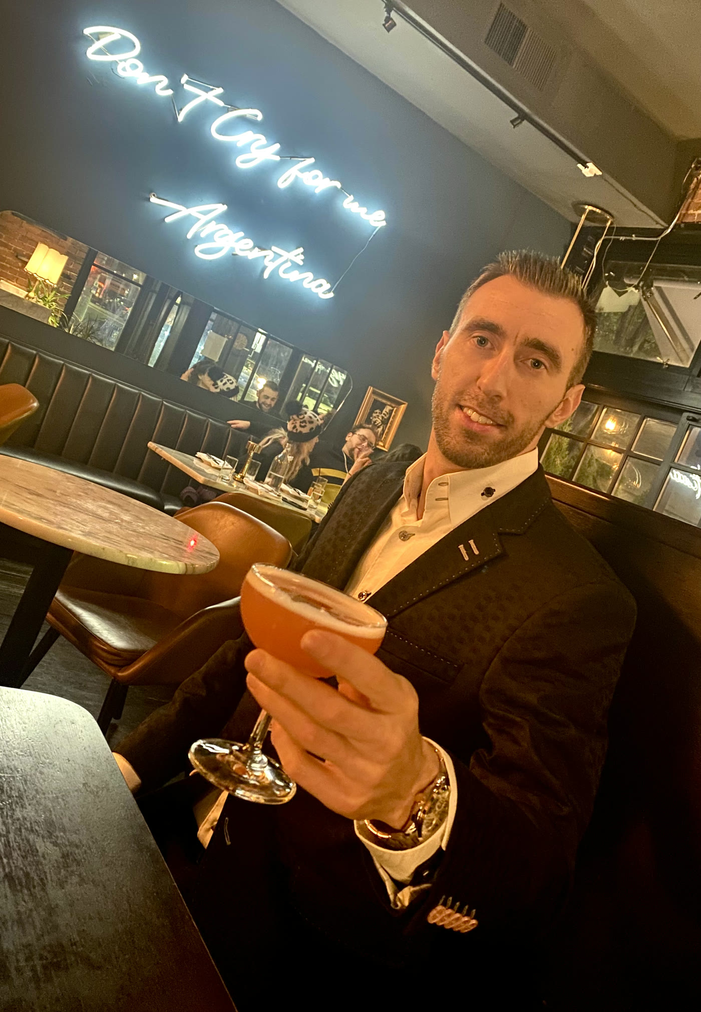 Pavel in a dark blazer and white shirt at a cocktail bar