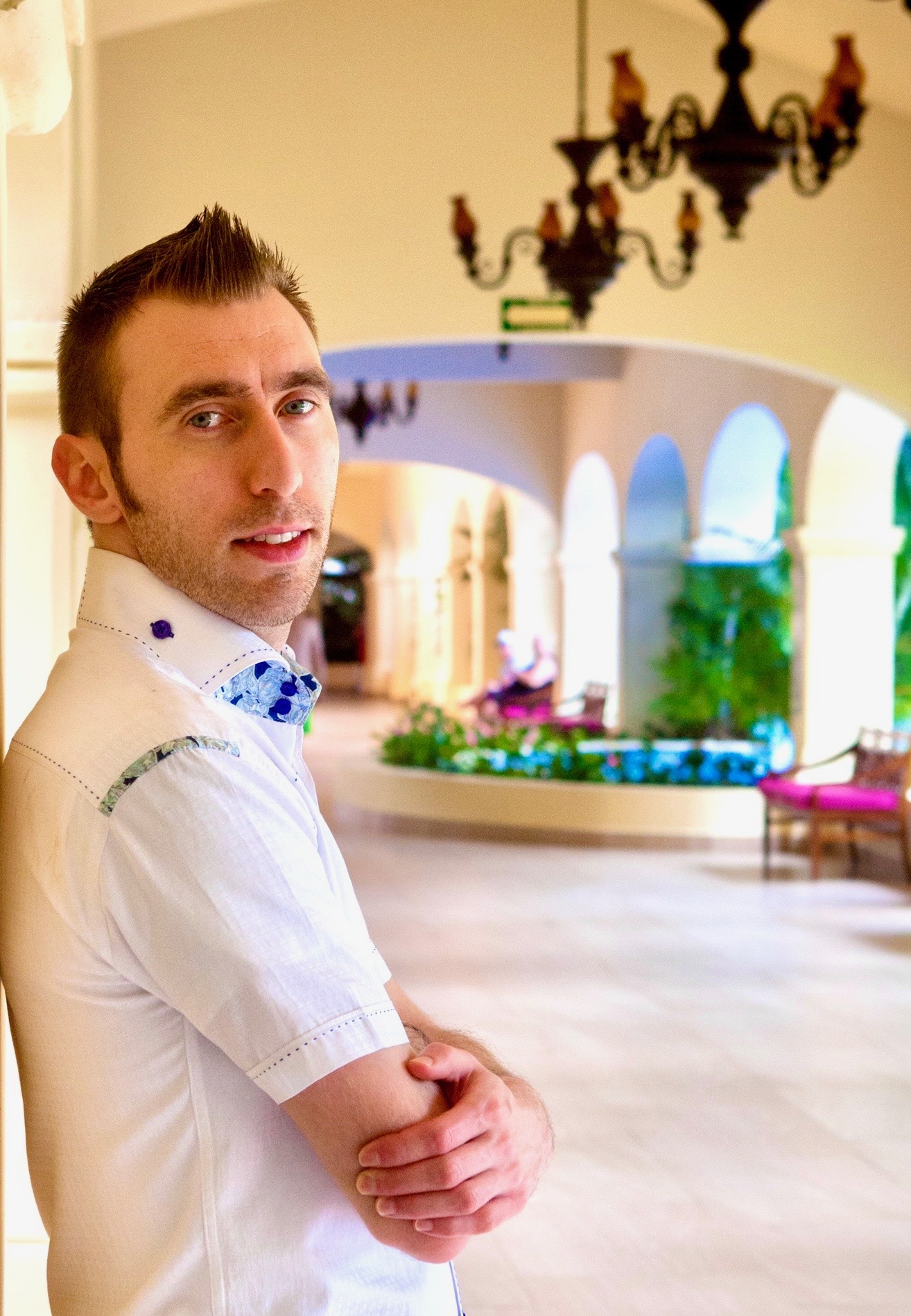 Pavel in a patterned white shirt in a sunlit courtyard